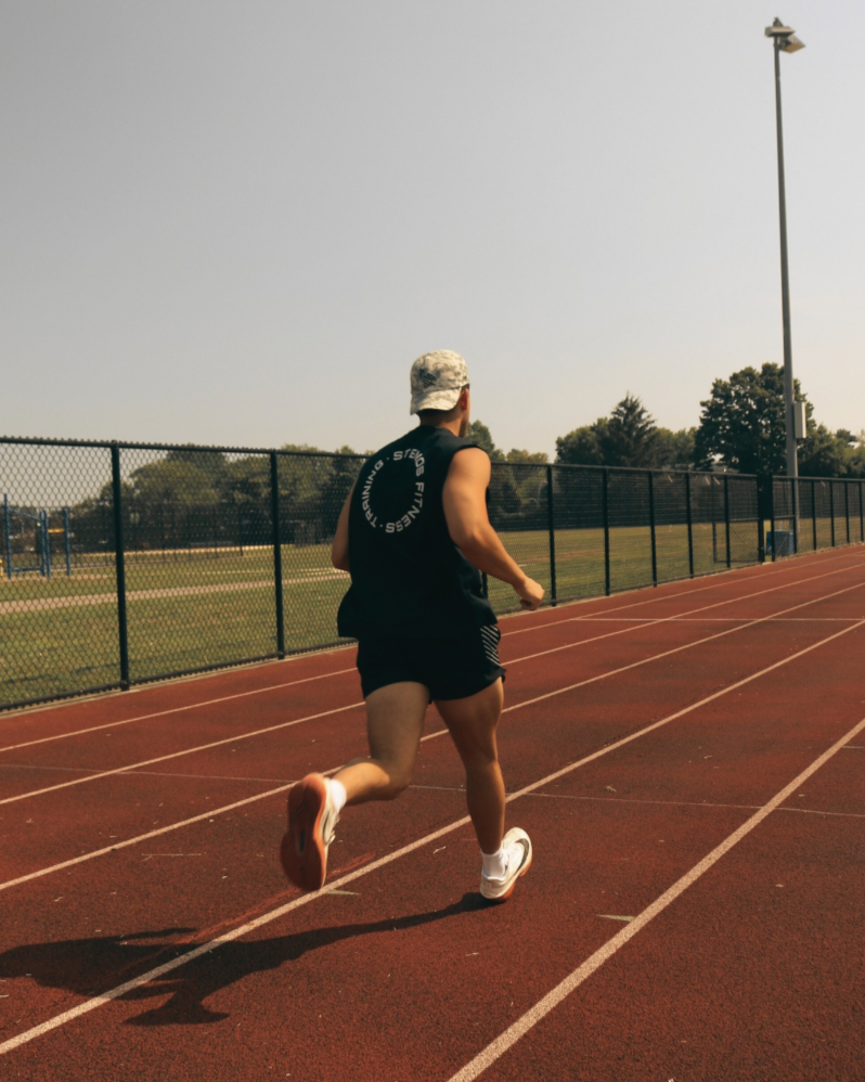 Person running on a track with a clear sky and trees in the background